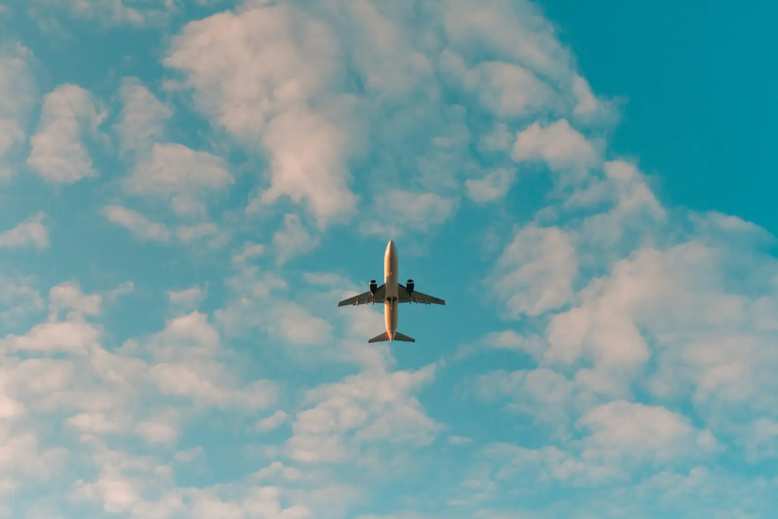 Avião a sobrevoar um céu azul com nuvens, evocando a mobilidade entre Portugal e o Brasil